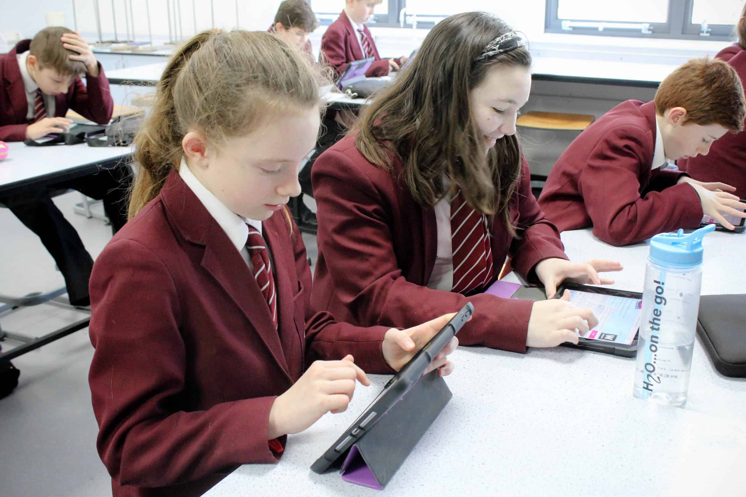 A photo of 2 students looking at a computer with the quote 